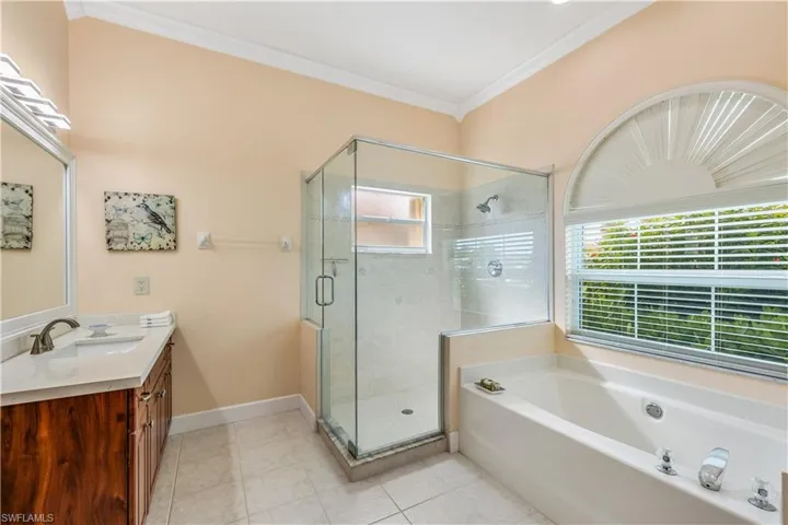 Bathroom with independent shower and bath, tile patterned floors, vanity, and ornamental molding
