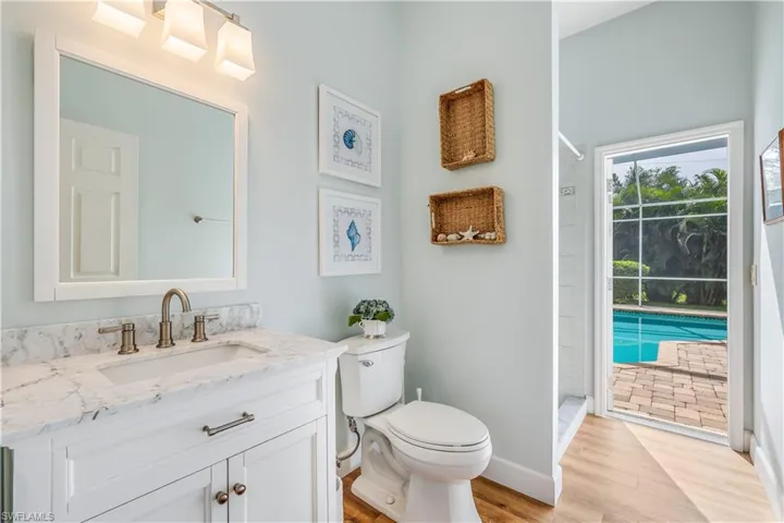 Bathroom featuring hardwood / wood-style flooring, toilet, vanity, and a tile shower