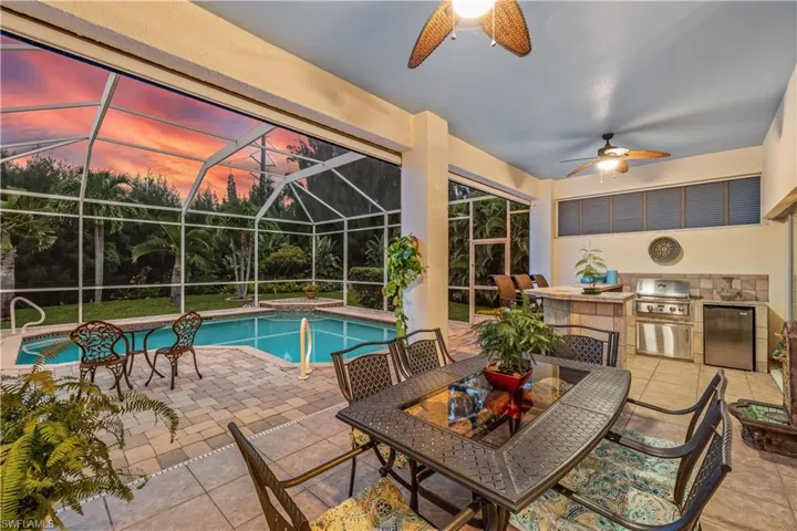 Pool at dusk featuring area for grilling, a lanai, grilling area, a patio area, and ceiling fan