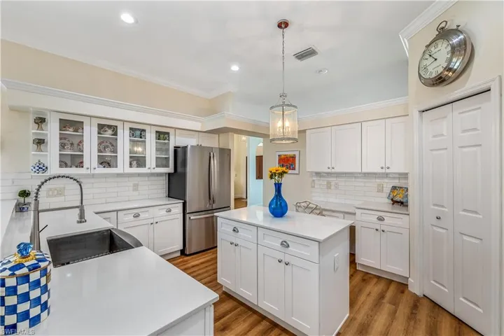 Kitchen with light hardwood / wood-style floors, sink, tasteful backsplash, and stainless steel fridge