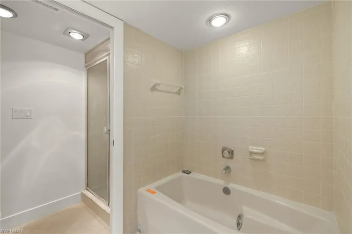 Bathroom featuring a shower stall, a tub, and tile patterned floors