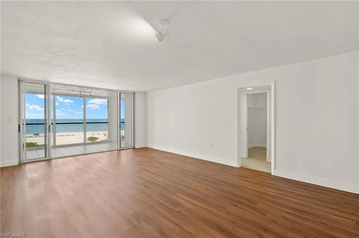 Empty room featuring a water view, floor to ceiling windows, wood finished floors, and a textured ceiling