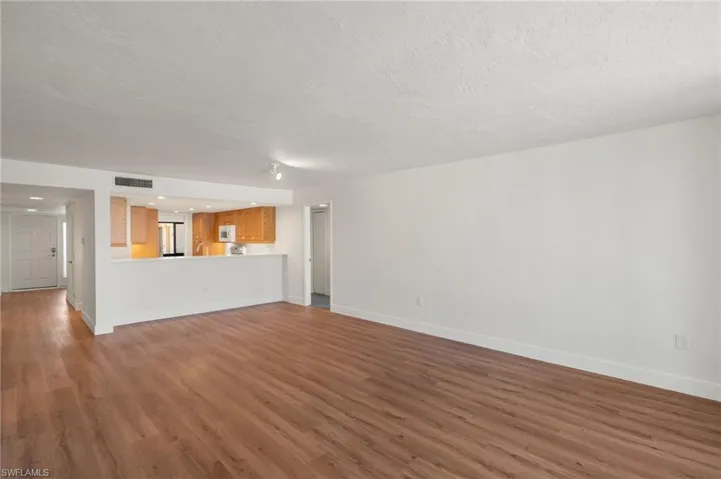 Unfurnished living room featuring dark wood-style flooring and a textured ceiling