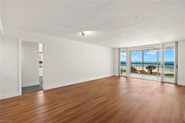 Unfurnished room featuring a water view, wood finished floors, a wall of windows, and a textured ceiling