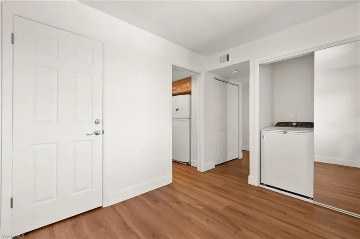 Unfurnished bedroom featuring washer / dryer, freestanding refrigerator, light wood-style flooring, and a closet