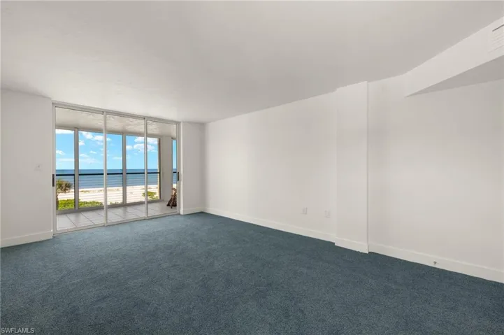 Carpeted spare room with expansive windows and a water view