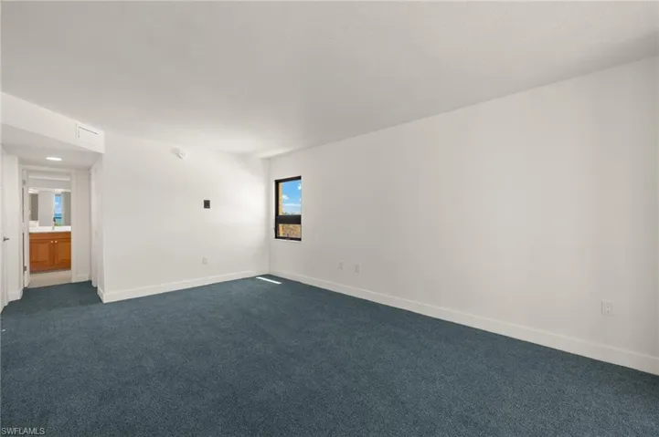 Unfurnished room with dark colored carpet and baseboards