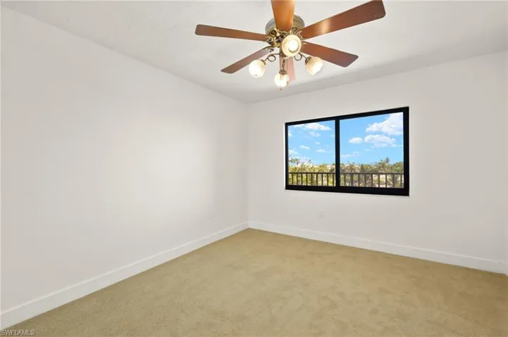 Empty room with light colored carpet and a ceiling fan