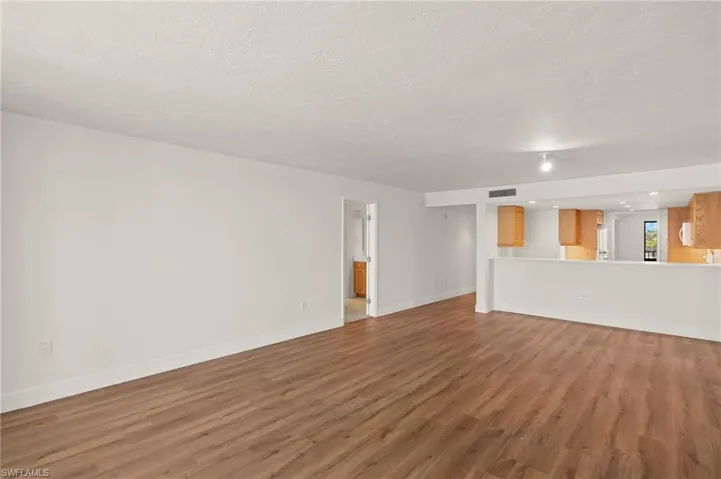 Unfurnished living room with wood finished floors and a textured ceiling