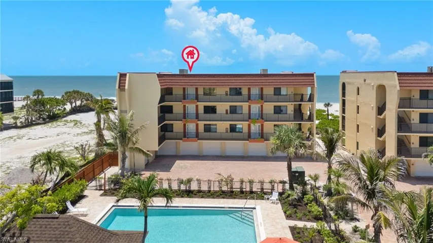 Community pool featuring view of water and beach and a patio