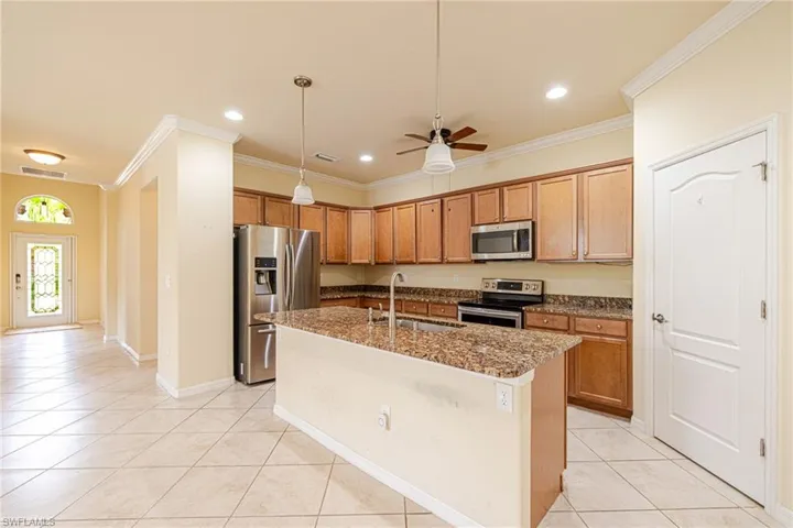 Kitchen featuring wood cabinetry, stainless steel appliances, a center island with a stone countertop, and recessed lighting
