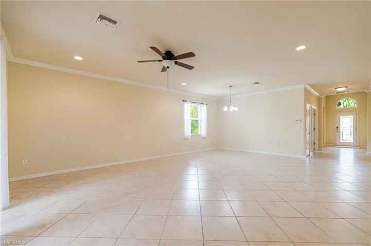 Spacious interior with tile flooring, crown molding, recessed lighting, and a ceiling fan