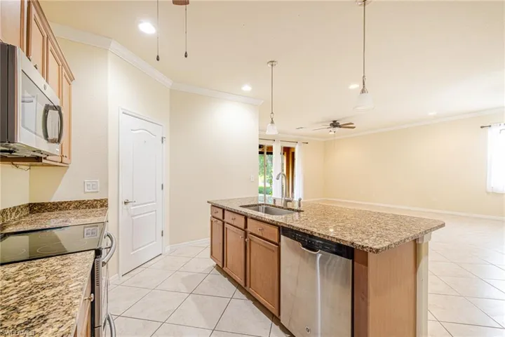 Kitchen island featuring a stainless steel sink, dishwasher, and granite countertop