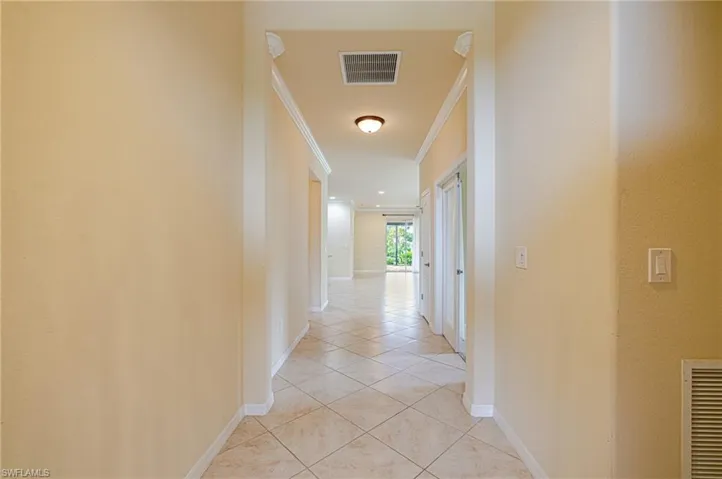 Hallway featuring light-toned tile flooring, recessed lighting, and crown molding accents