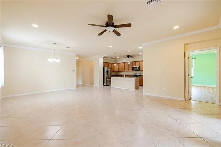 Spacious open-concept interior with tile flooring, crown molding, a ceiling fan, and recessed lighting