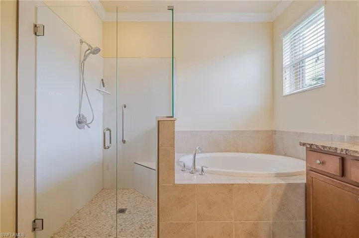 Glass-enclosed shower with pebble-finish flooring and a built-in bench