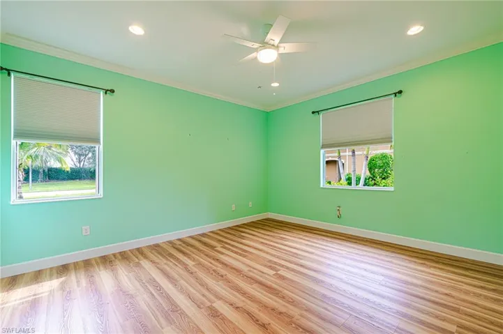 Wood-finish flooring with crown molding, recessed lighting, and a ceiling fan