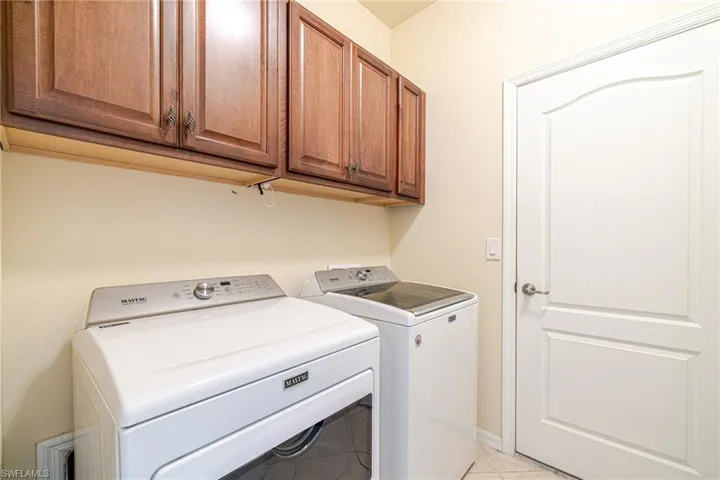 Laundry area featuring wood cabinetry, a paneled door, and tile flooring