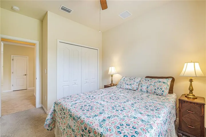 Carpeted flooring, bi-fold closet doors, ceiling-mounted light fixture, and a doorway leading to a tiled room