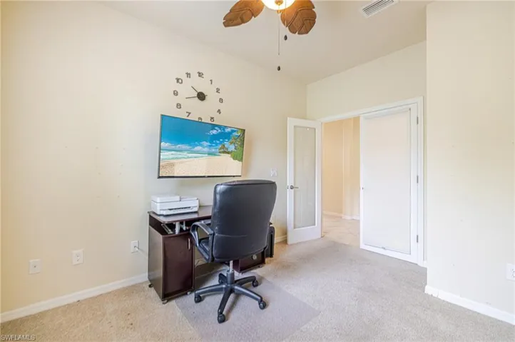 Ceiling fan with tropical-inspired blades, carpet flooring, double door entry, and integrated ceiling lighting