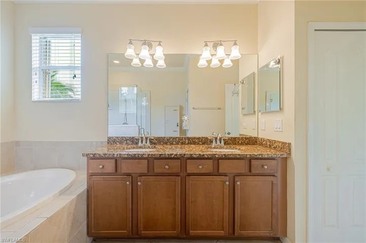 Dual vanity with a stone countertop, individual mirrors, and sconce lighting