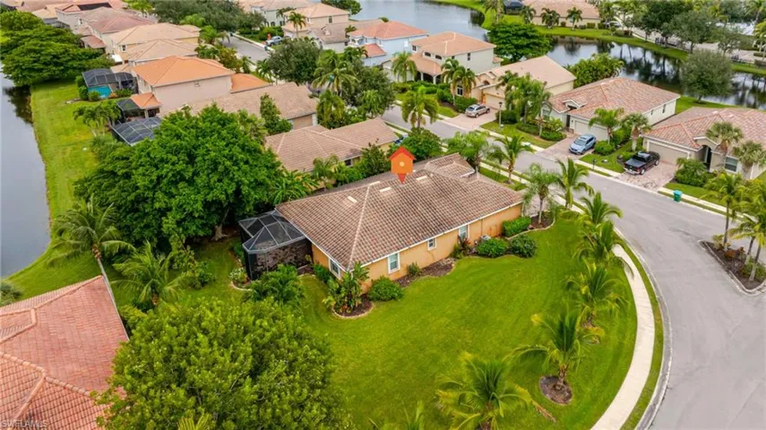 Tile roof residence with extensive manicured lawn, established landscaping, and screened enclosure