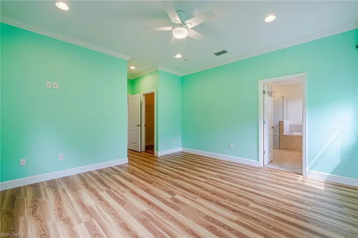 Wood-finish flooring, recessed lighting, crown molding, ceiling fan, and built-in closet