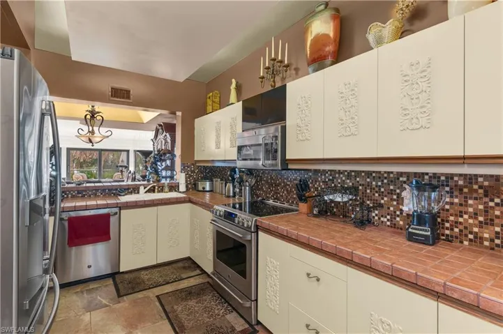 Kitchen featuring appliances with stainless steel finishes, visible vents, a sink, and backsplash