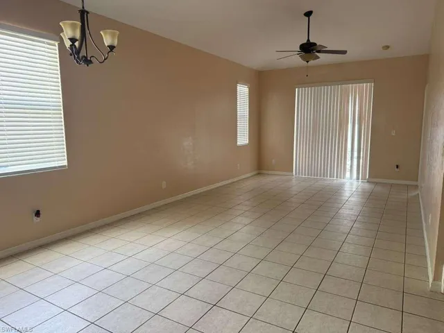 Unfurnished room with light tile patterned flooring, a chandelier, and a ceiling fan