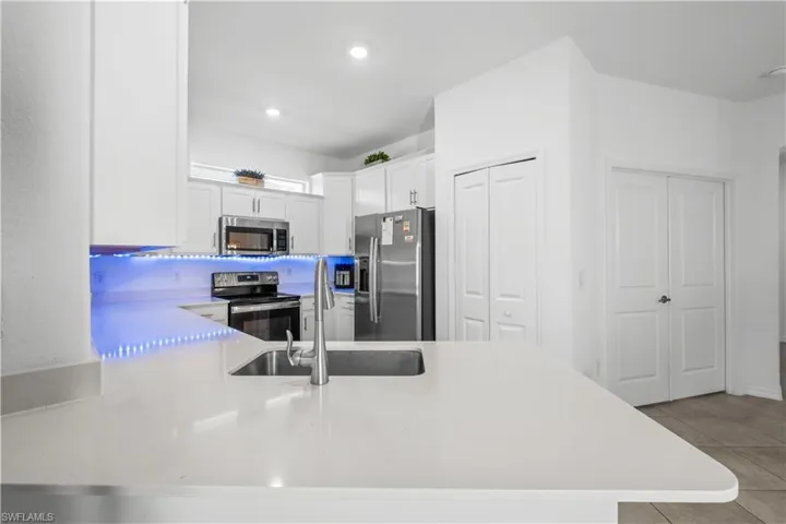 Kitchen featuring white shaker cabinetry, stainless steel appliances, white countertops, and a stainless steel sink with a high-arc faucet