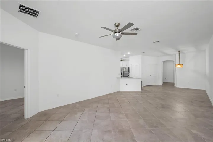 Spacious living area featuring tile flooring, a ceiling fan, and a contemporary pendant light fixture
