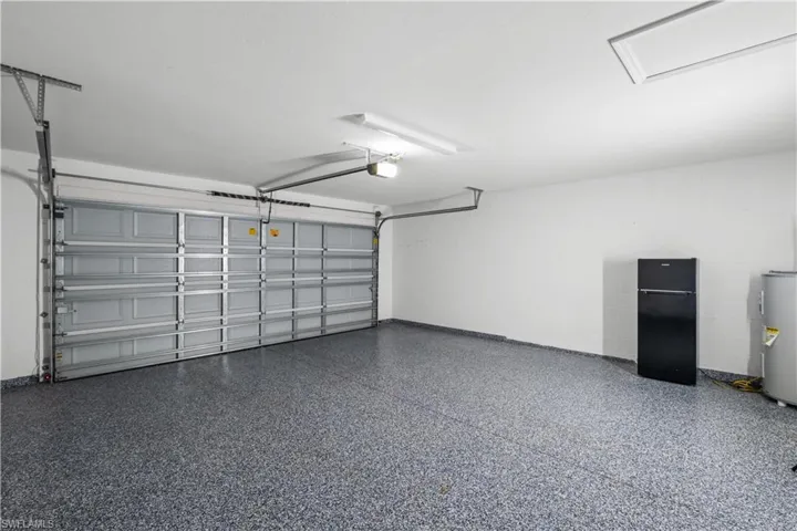 Epoxy coated garage floor, single overhead garage door, overhead lighting, access panel, and painted walls