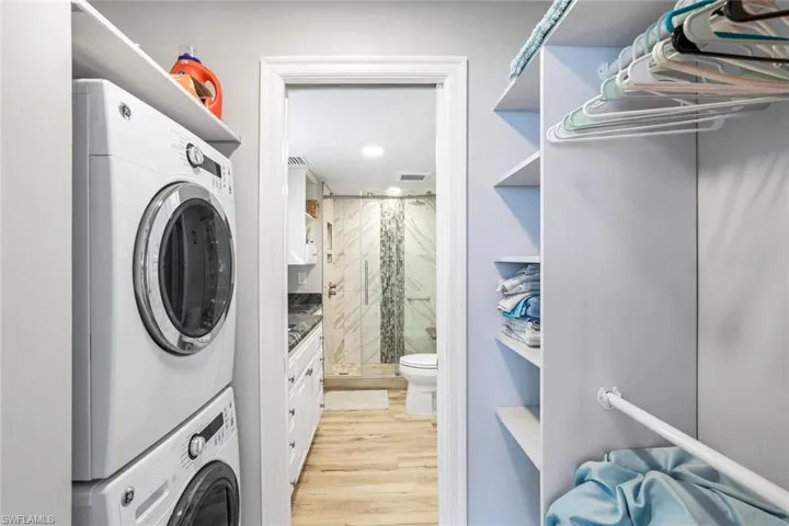 Laundry area with stacked washer / dryer and light wood-type flooring