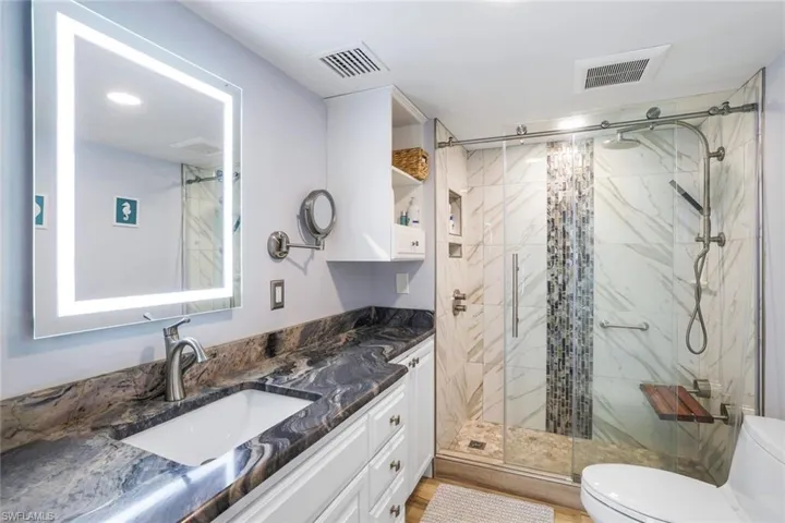 Bathroom featuring walk in shower, hardwood / wood-style flooring, toilet, and vanity