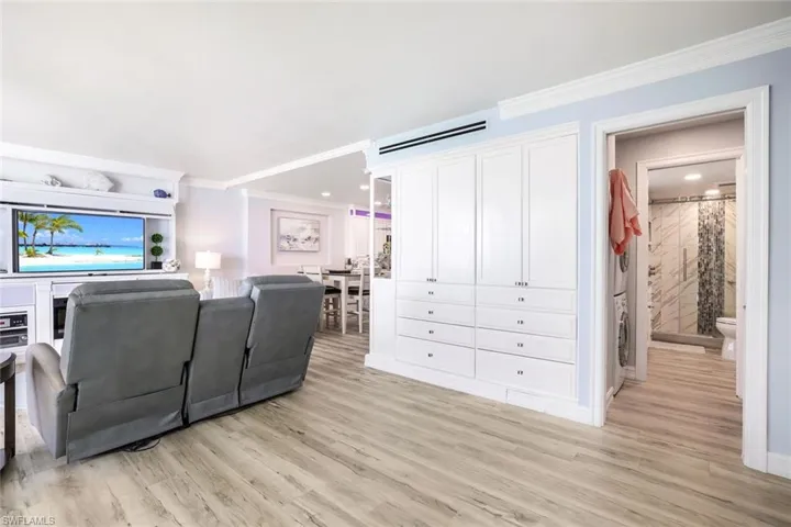 Living room with light hardwood / wood-style floors, washer / dryer, and crown molding