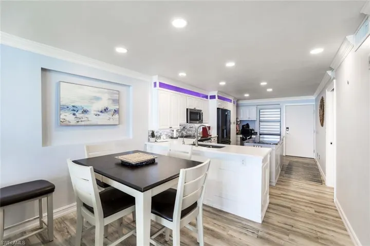 Dining room with sink, light hardwood / wood-style flooring, and crown molding
