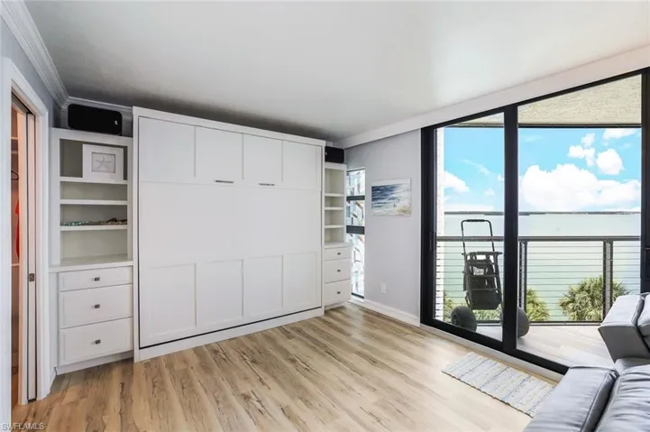 Unfurnished bedroom featuring crown molding, light wood-type flooring, and multiple windows