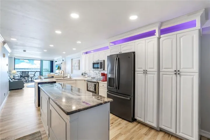 Kitchen featuring black fridge with ice dispenser, sink, light wood-type flooring, and crown molding
