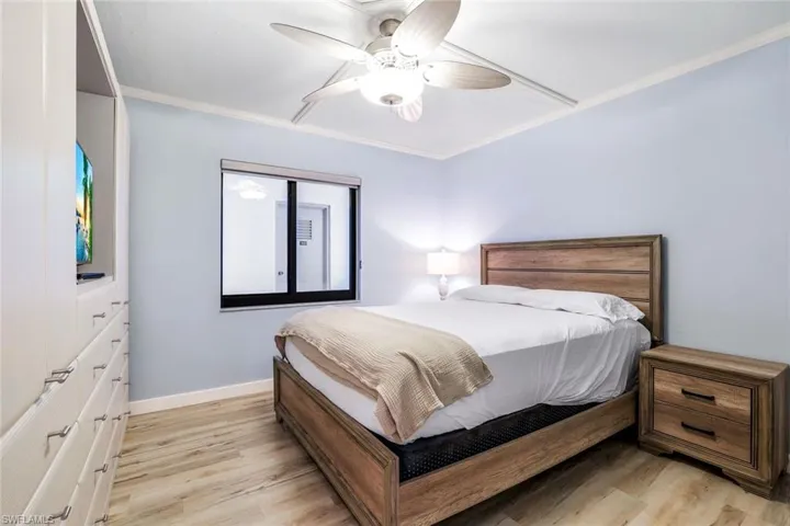 Bedroom featuring ornamental molding, light wood-type flooring, and ceiling fan