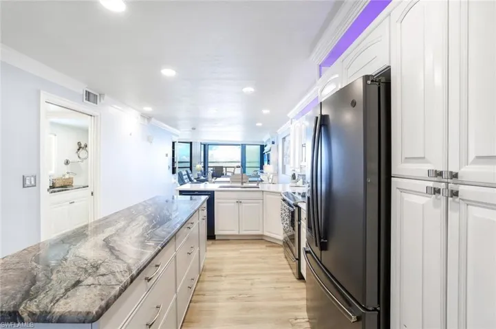 Kitchen with white cabinets, appliances with stainless steel finishes, sink, and light wood-type flooring