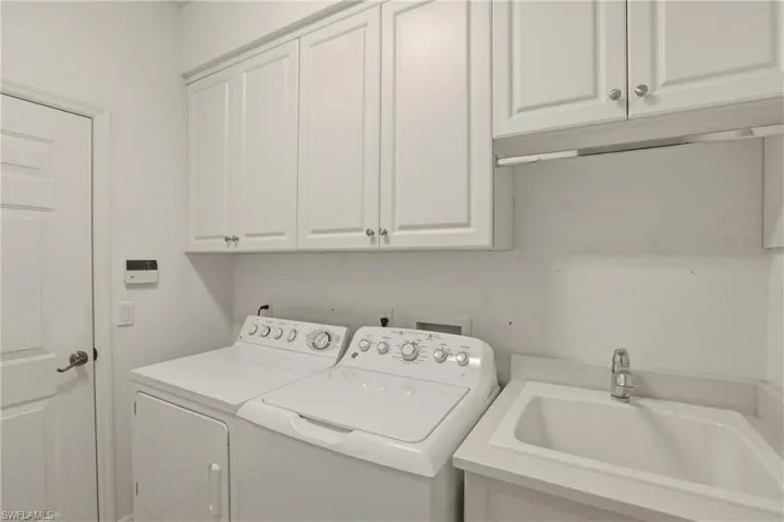 Laundry room featuring a sink and washer and clothes dryer and cabinetry