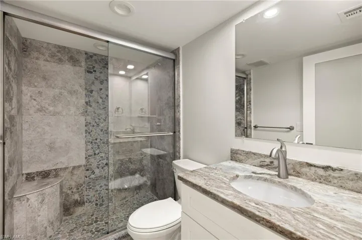 Bathroom featuring vanity, toilet, and an enclosed shower