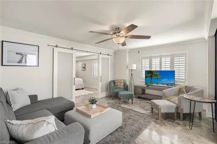 Living room featuring plenty of natural light, ornamental molding, and a barn door