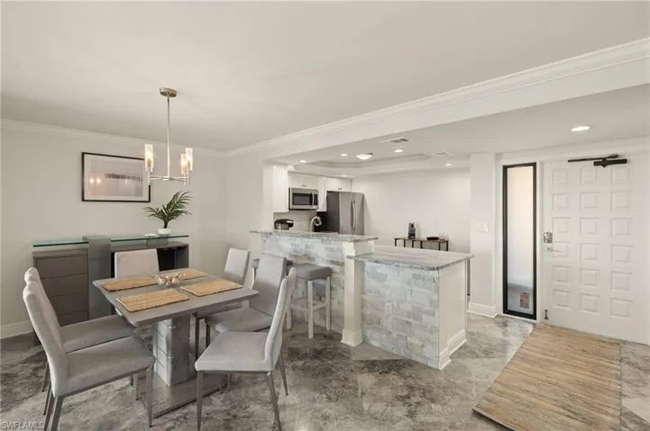 Dining area with an inviting chandelier, ornamental molding, and sink