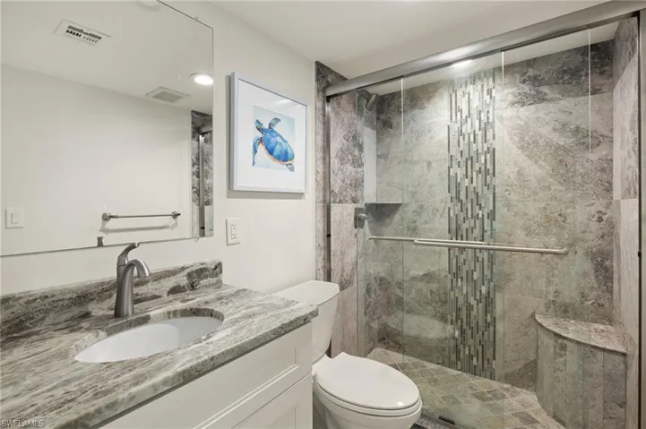 Bathroom with toilet, vanity, and walk in shower