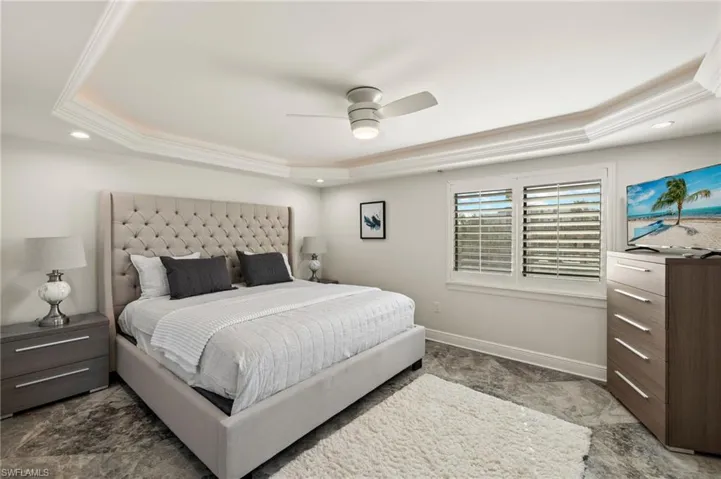 Bedroom featuring a raised ceiling, crown molding, and ceiling fan