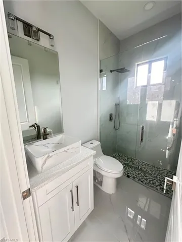 Bathroom featuring walk in shower, vanity, and toilet