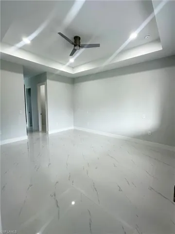 Empty room with ceiling fan and a raised ceiling