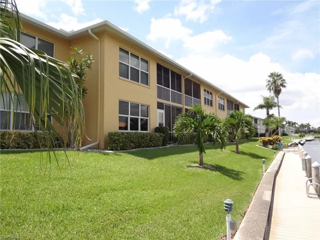 View of rear of building with a lawn, lush landscaping, & dock