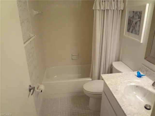 Full bathroom (guest) featuring tile patterned floors, shower / bath combo, toilet, and vanity
